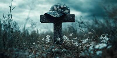 Memorial tribute featuring a camouflage cap resting on a cross surrounded by wildflowers in a serene landscape photo