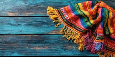 Colorful woven blanket draped on rustic wooden table showcasing vibrant texture and design photo