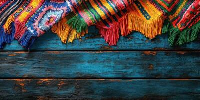 Colorful woven textile draped over rustic blue wooden surface with intricate patterns and vibrant fringe details photo