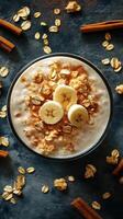 Creamy banana oatmeal bowl topped with cinnamon and oats on a dark stone surface photo
