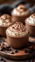 Creamy desserts topped with chocolate and whipped cream served in elegant brown cups on a rustic wooden surface photo