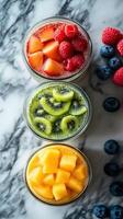 Colorful fruit parfaits arranged in jars on a marble surface with fresh berries nearby photo