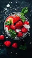 Fresh berry dessert with chia seeds, coconut, and mint in a dark setting photo