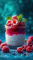 Raspberry chia pudding in a glass topped with fresh berries and mint leaves on a vibrant blue background photo