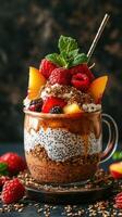 Decadent layered dessert featuring fruits and chia seeds served in a glass cup with mint on top photo