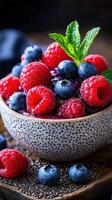 Fresh berries in a textured bowl with mint leaves on a wooden surface showcasing vibrant colors photo