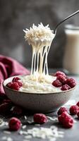 Creamy rice pudding with fresh raspberries and drizzled milk in a rustic bowl on a textured background photo