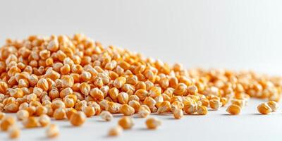 Dried corn kernels spread out on a light surface, showcasing their texture and color in natural lighting photo
