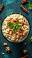 Creamy rice pudding topped with cinnamon and mint leaves on a textured blue background photo