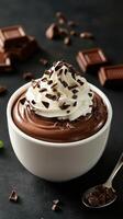Indulgent chocolate mousse topped with whipped cream and chocolate shavings served in a white bowl photo