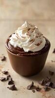 Rich chocolate mousse topped with whipped cream and chocolate shavings in a dark bowl on a wooden surface photo