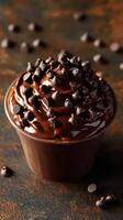 Decadent chocolate dessert topped with chocolate chips served in a cup on a rustic wooden surface photo