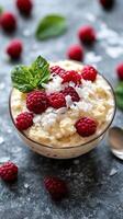Delicious coconut rice pudding topped with fresh raspberries and mint leaves in a glass bowl photo