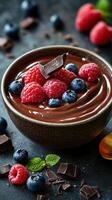 Delicious chocolate mousse topped with fresh berries in a rustic bowl on a dark table photo