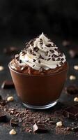 Decadent chocolate dessert topped with whipped cream and chocolate shavings served in a glass dish on a dark background photo