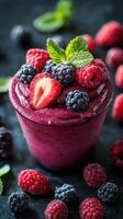 Delicious berry smoothie topped with fresh fruit and mint on a dark background photo