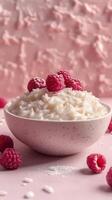 Creamy rice pudding topped with fresh raspberries on a soft pink background photo