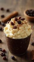 Creamy rice pudding topped with cinnamon and raisins served in a glass on a wooden table photo