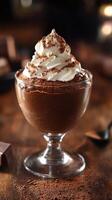 Decadent chocolate mousse topped with whipped cream and cocoa powder served in a glass dessert dish photo