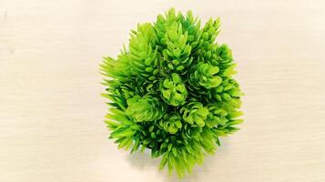 Artificial plastic grass in a pot in the center on a light colored wooden background. photo