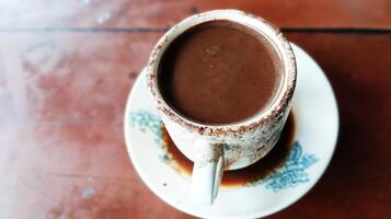 Chocolate flavored coffee in a white cup with a small saucer on a wooden table images photo