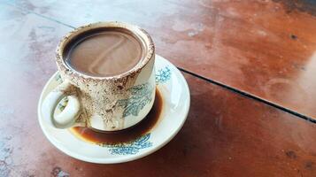 Chocolate flavored coffee in a traditional white cup with a small saucer on the table. photo