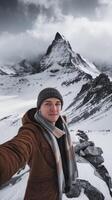 A man taking a selfie in front of a snowy mountain photo