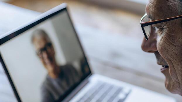 A closeup of an elderly mans face illuminated by the soft light of a computer screen as he immerses himself in a virtual seminar about biohacking and digital health management. photo