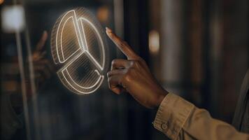 A closeup shot of a hand reaching out to interact with a shimmering holographic graphic showcasing a 3D pie chart that rotates in response to touch.. photo