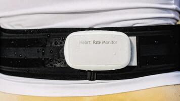 A detailed view of a heart rate monitor belt clinging tightly to a torso with a small screen showing live measurements and moisture droplets indicating physical exertion.. photo
