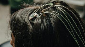 A closeup of electrodes p on the scalp of an elderly woman capturing the intricate details of the sensors connected to a flexible hightech neurofeedback device.. photo