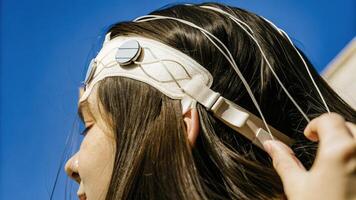 A futuristic headband featuring embedded EEG sensors that connect wirelessly to a mobile app visualizing neurological data and mental states. The headbands fabric is shown. photo