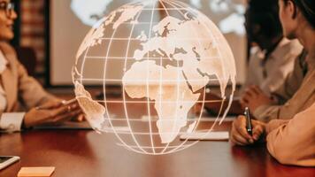 A holographic representation of global offices and teams rotates in the center of the table while attendees exchange ideas about collaboration and crossborder initiatives.. photo
