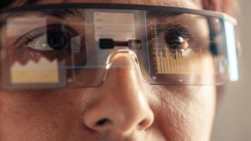 A closeup of a person wearing augmented reality glasses looking intently at a floating holographic interface displaying complex data and analytics illustrating advanced technology. photo