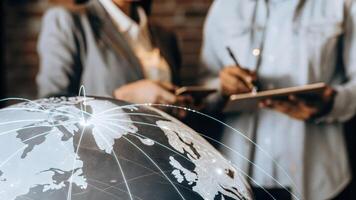 A closeup of a holographic projection of a digital globe with animated data flows highlighting global market connections as fascinated viewers take notes.. photo