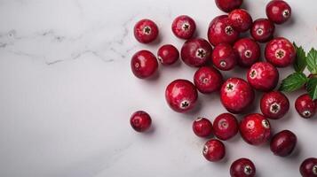 Fresh cranberries scattered on a marble surface, with a mint leaf accent. photo