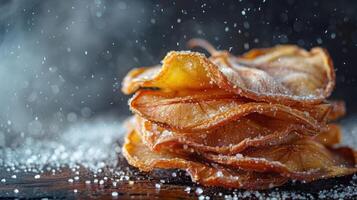 A close-up of stacked dried fruit slices, dusted with sugar, on a wooden surface. photo