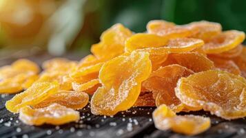 A pile of vibrant, sugary dried mango slices on a wooden surface. photo