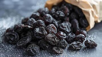 A bag of dried prunes spilled on a surface, showcasing their rich color and texture. photo