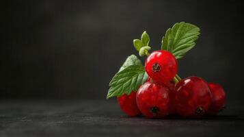 A cluster of red currants with green leaves against a dark background. photo