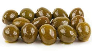 A cluster of shiny green olives arranged on a white surface. photo