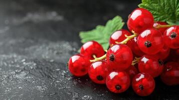 A close-up of fresh red currants on a dark surface, showcasing their vibrant color and texture. photo