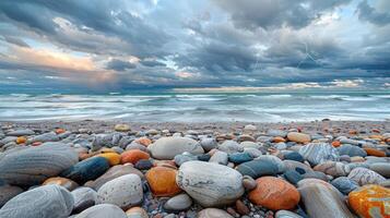 A serene beach scene with colorful pebbles and dramatic clouds over the ocean waves. photo