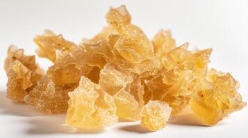 A pile of translucent, golden resin-like crystals on a white background. photo