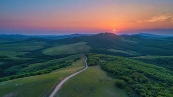 A serene landscape at sunset, showcasing rolling hills and a winding road. photo