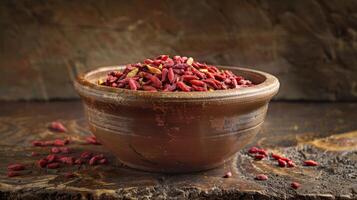 A rustic bowl filled with dried goji berries on a textured wooden surface. photo