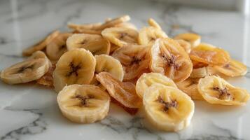 A pile of dried banana slices arranged on a marble surface, showcasing their texture and color. photo