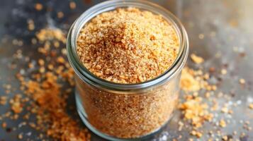 A jar filled with brown sugar, surrounded by scattered granules. photo