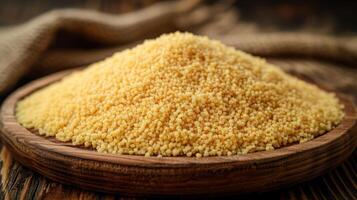 A mound of uncooked couscous in a wooden bowl, showcasing its fine grain texture. photo