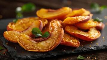 Dried peach slices arranged on a slate surface, garnished with mint leaves. photo